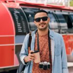 young male photographer with drink and photocamera